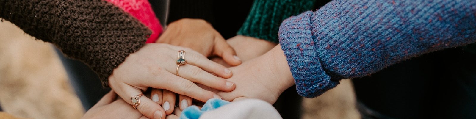 person in red sweater holding babys hand