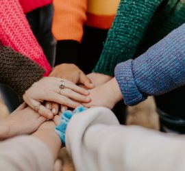 person in red sweater holding babys hand